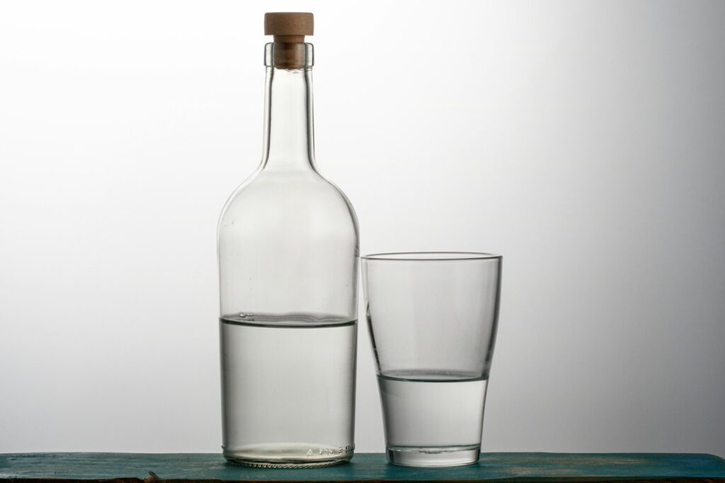 Two clear drinking glasses beside bottle