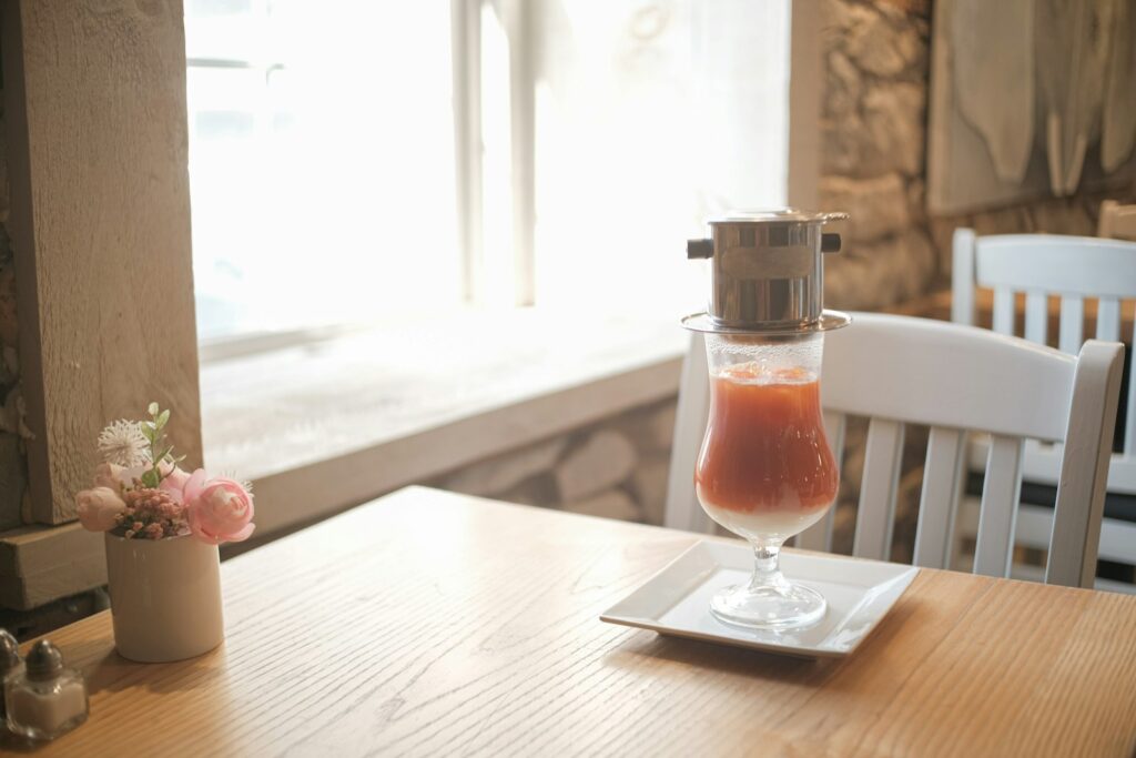 Coffee dripper over a colorful drink on a cafe table