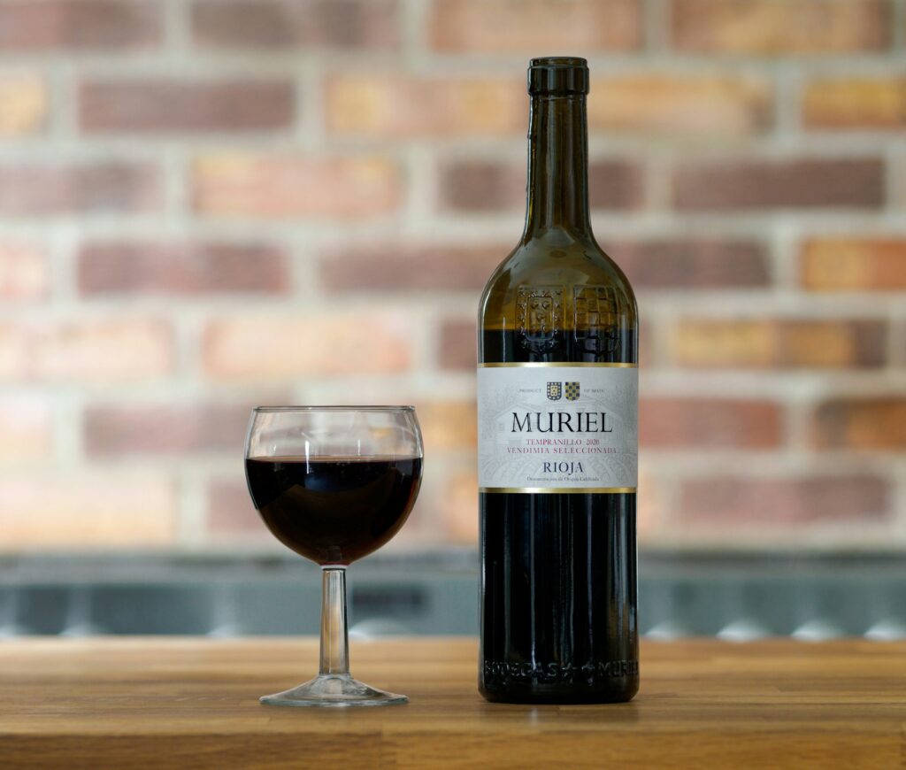 A bottle of wine next to a glass of wine