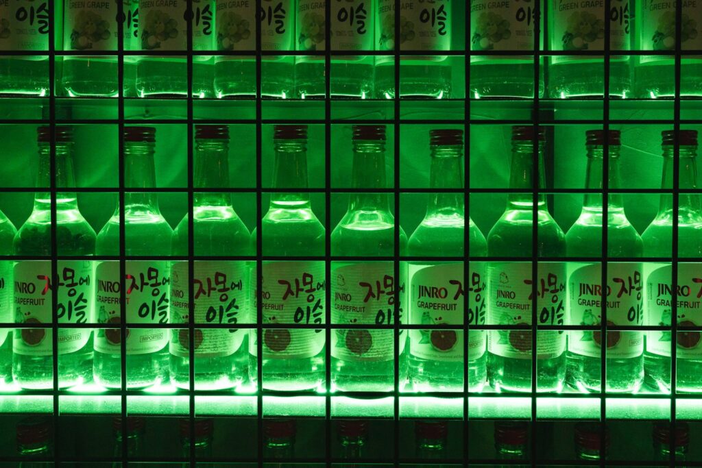 Green bottles of soju lined up on a shelf