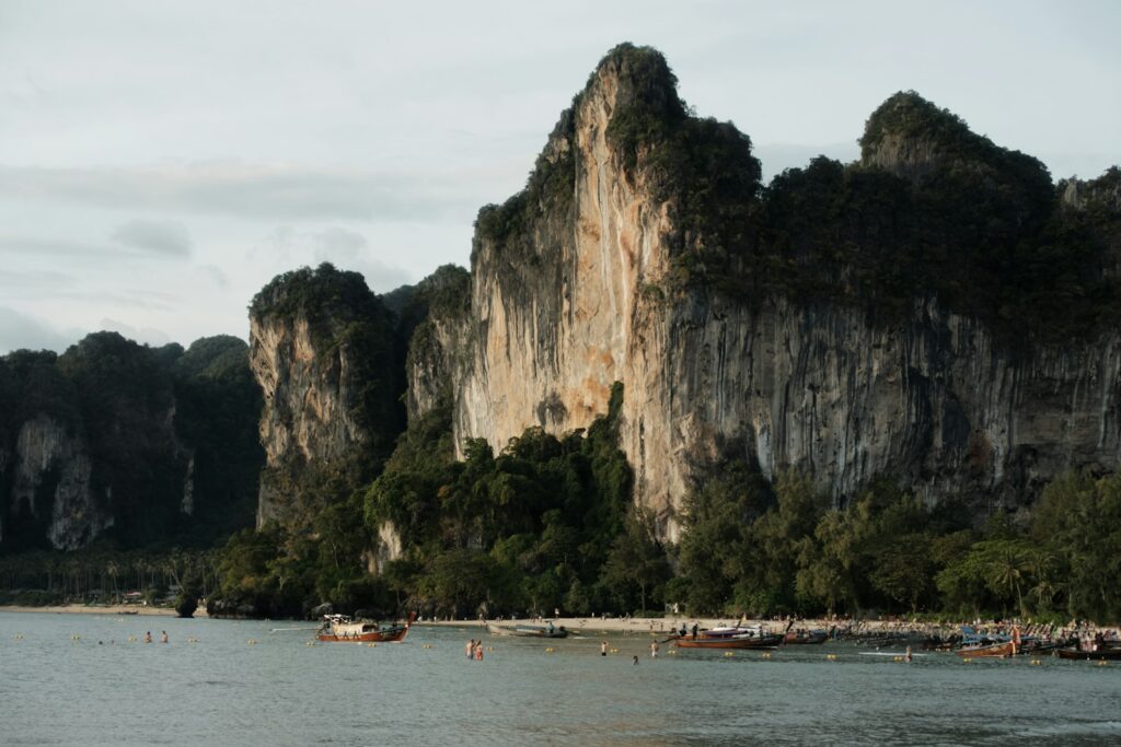 Jagged limestone cliffs rise above a tropical beach