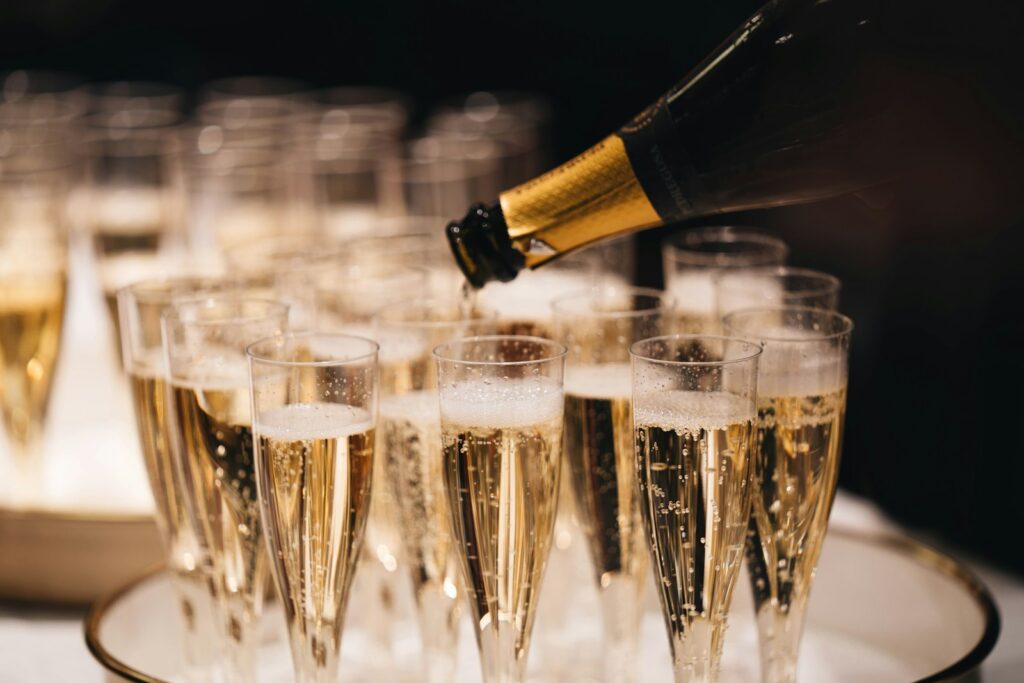 Champagne pouring from a bottle into a group of flutes on a tray