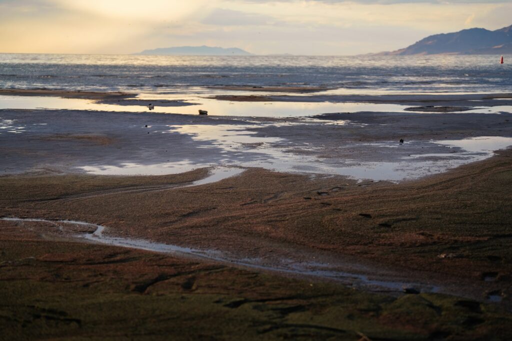 Beach at low tide with reflections and distant hills