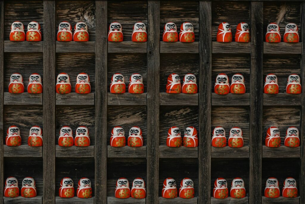 Rows of small daruma dolls displayed on wooden shelves