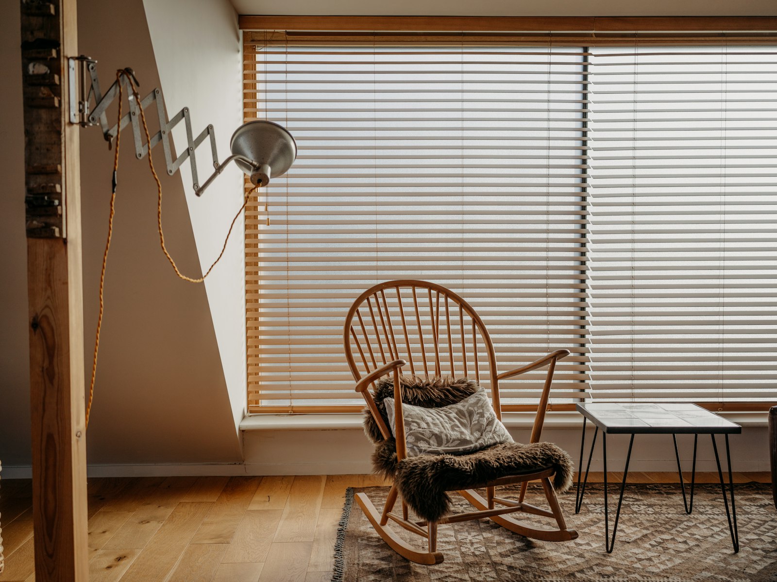 Rocking chair by window with blinds and side table