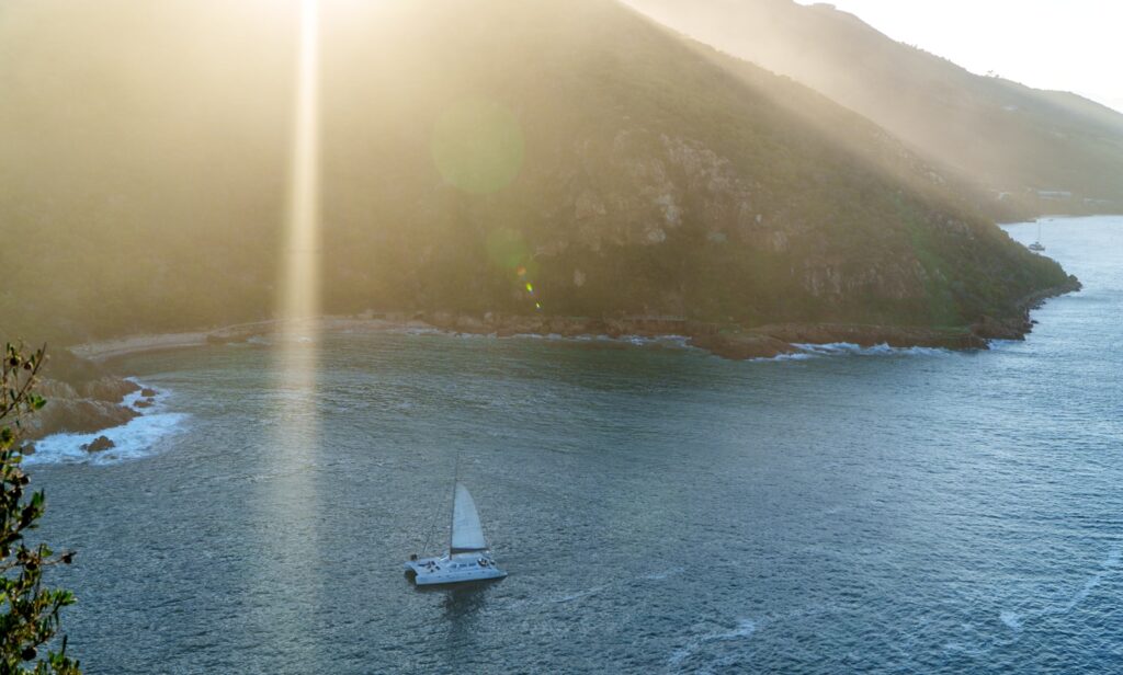 Sailboat on the water near a rocky coastline at sunset