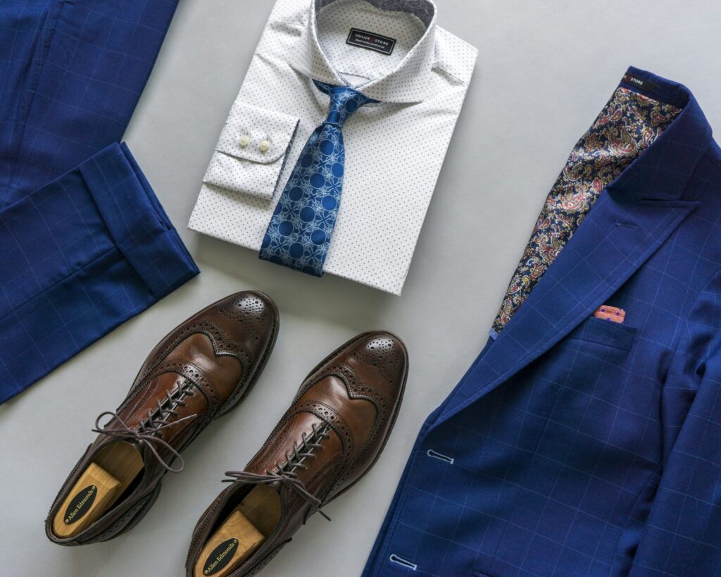 Blue and white necktie beside brown leather shoes
