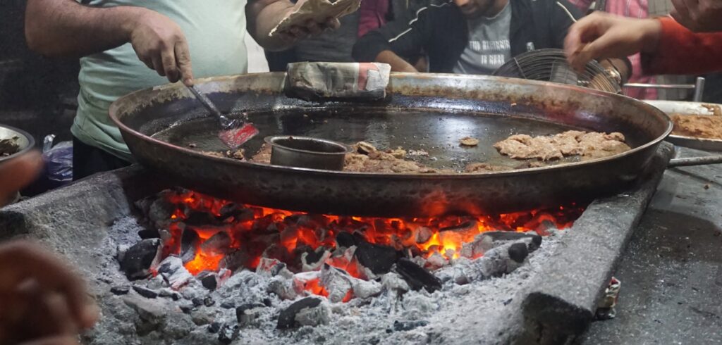 A group of people standing around a large pan of food