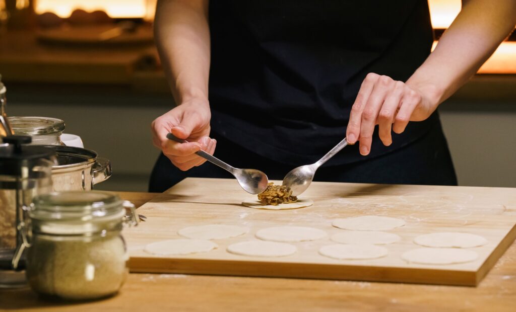 Hands filling dough circles with food mixture