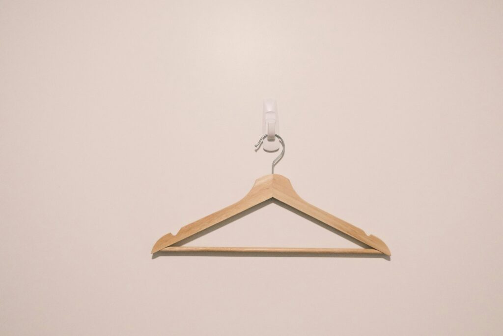 A wooden hanger with a hook on a white wall