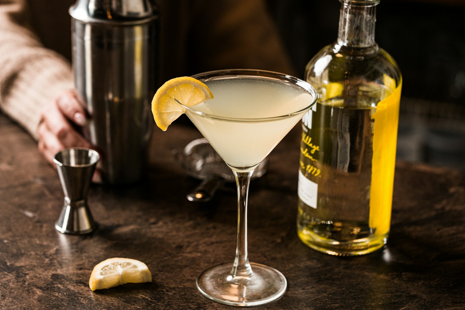A martini with a lemon slice and bar tools