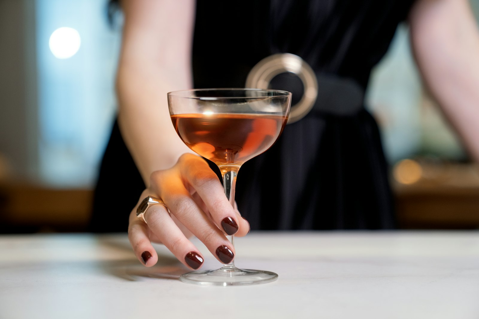 A woman's hand holding a wine glass with a drink in it
