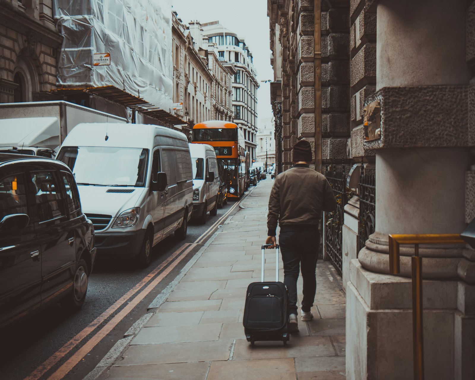 Man holding luggage walking near road during daytime
