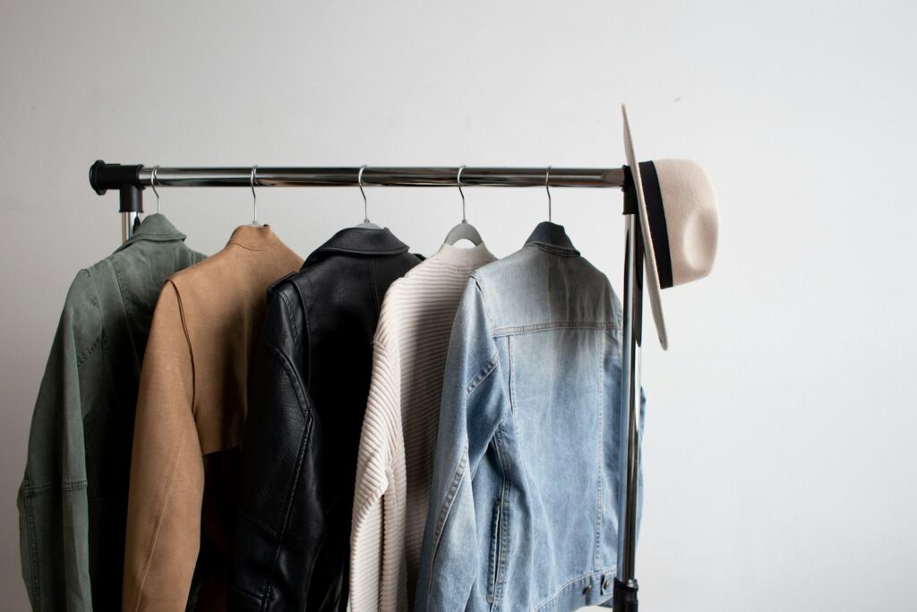 One cowboy hat and five jackets hanged on clothes rack