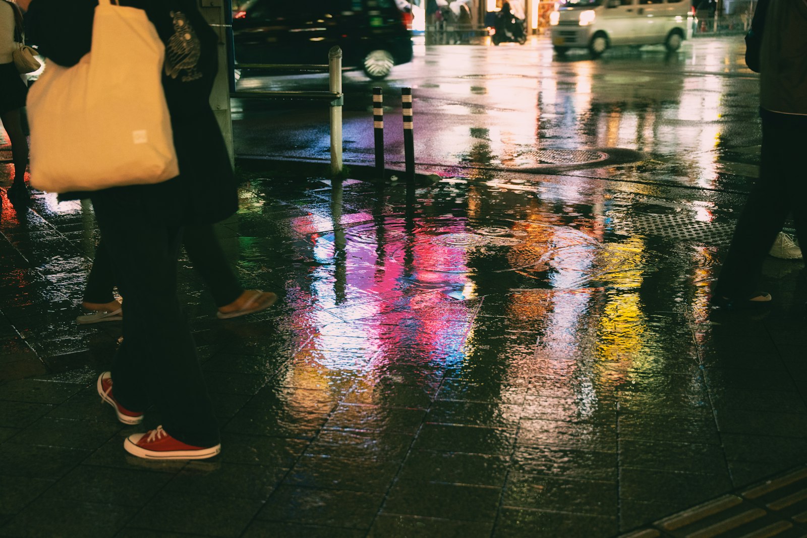 People walking on wet city street with neon reflections
