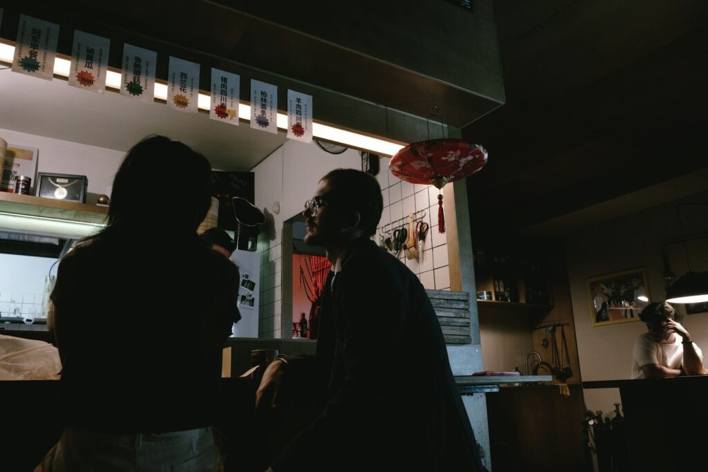 People silhouetted at a bar with a red lantern