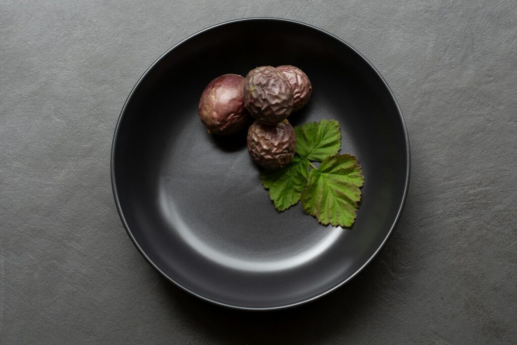 A black plate topped with three figs and a leaf