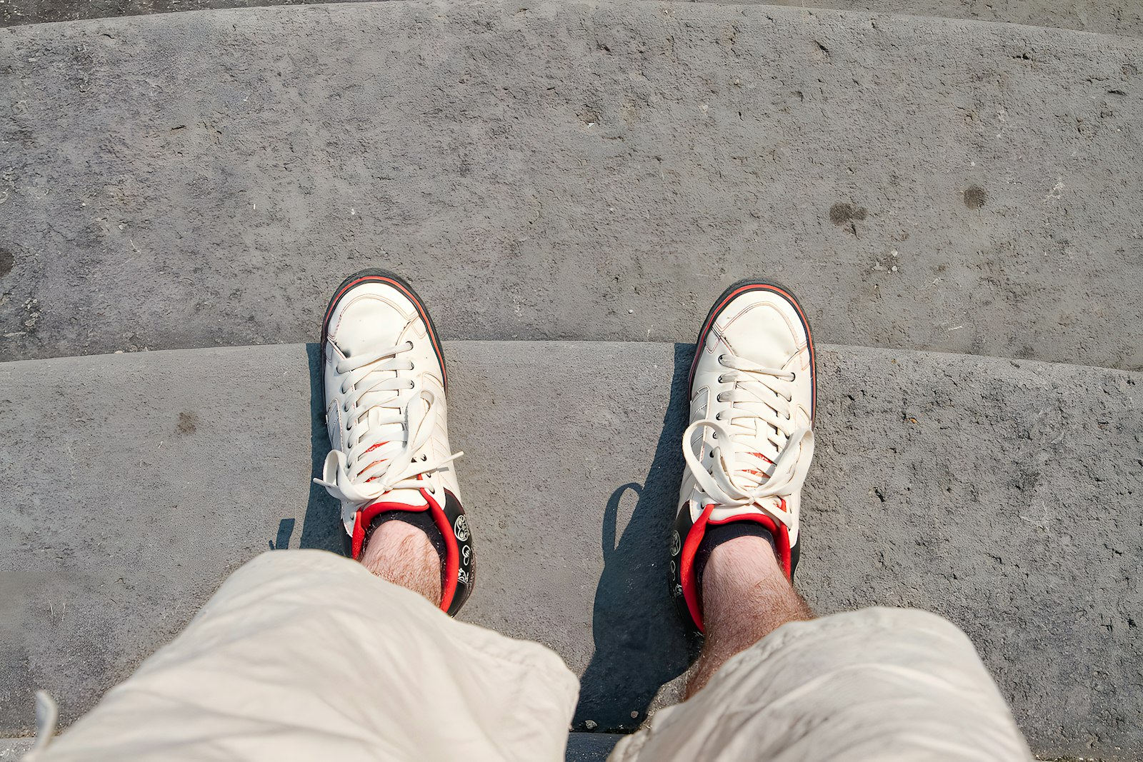 Person wearing white sneakers standing on concrete steps