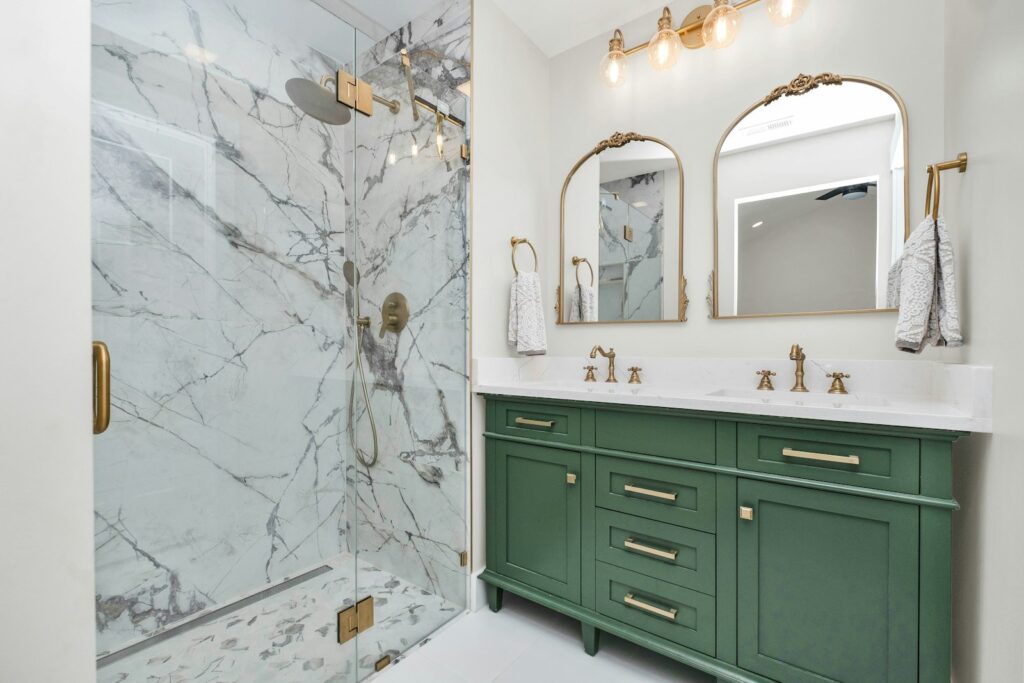 A bathroom with green cabinets and a marble shower