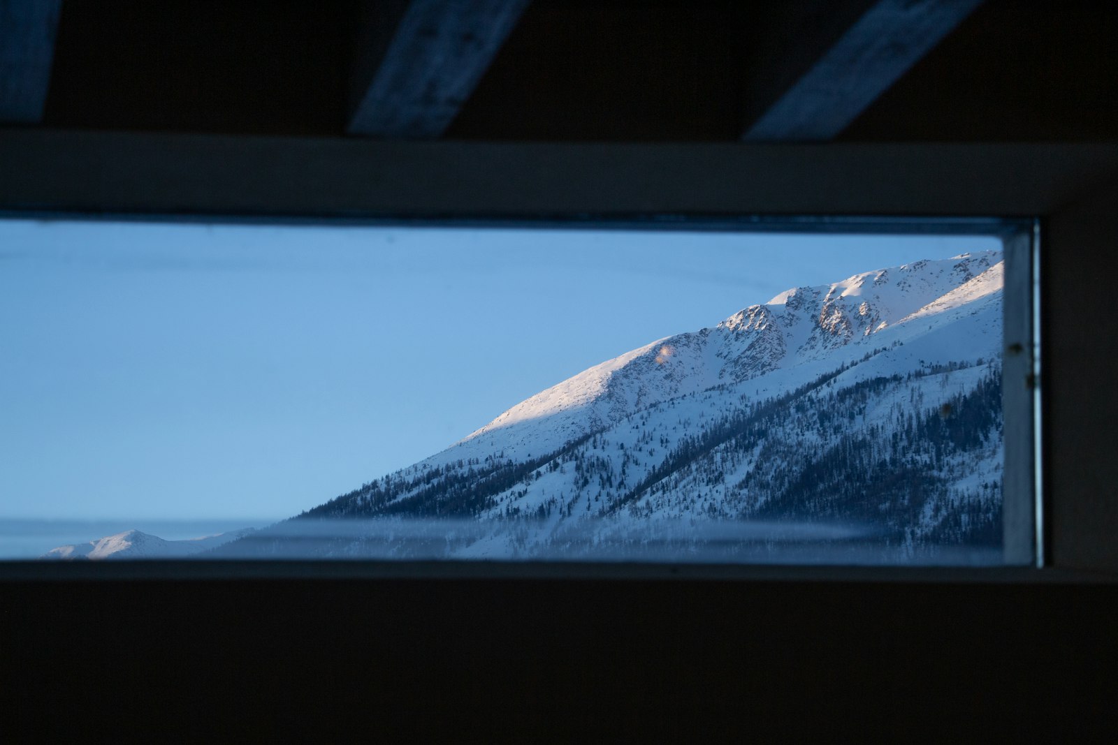 Snow-covered mountain range seen through a window