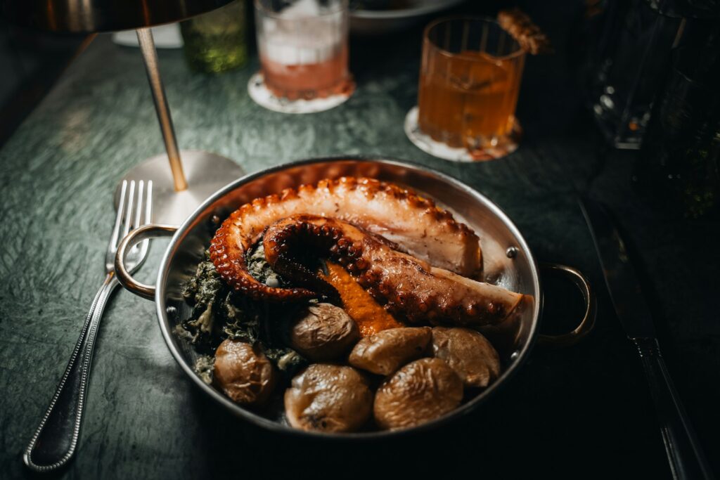 A cooked octopus dish with potatoes and greens