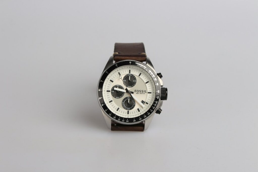 Round silver-colored fossil chronograph watch at 9:22 with brown leather band
