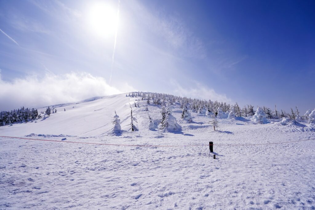 Bright sun shines over a vast, snow-covered mountain landscape