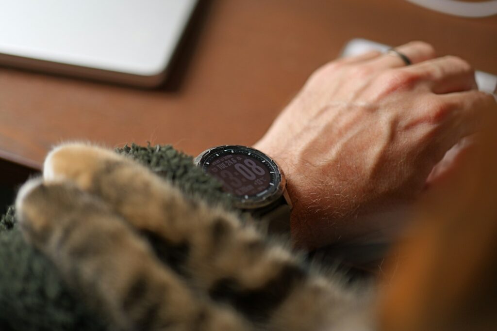 A hand working while a cat snuggles