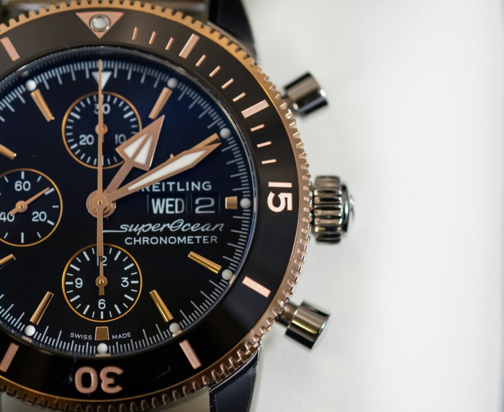 Round black and gold-colored brietling chronograph watch