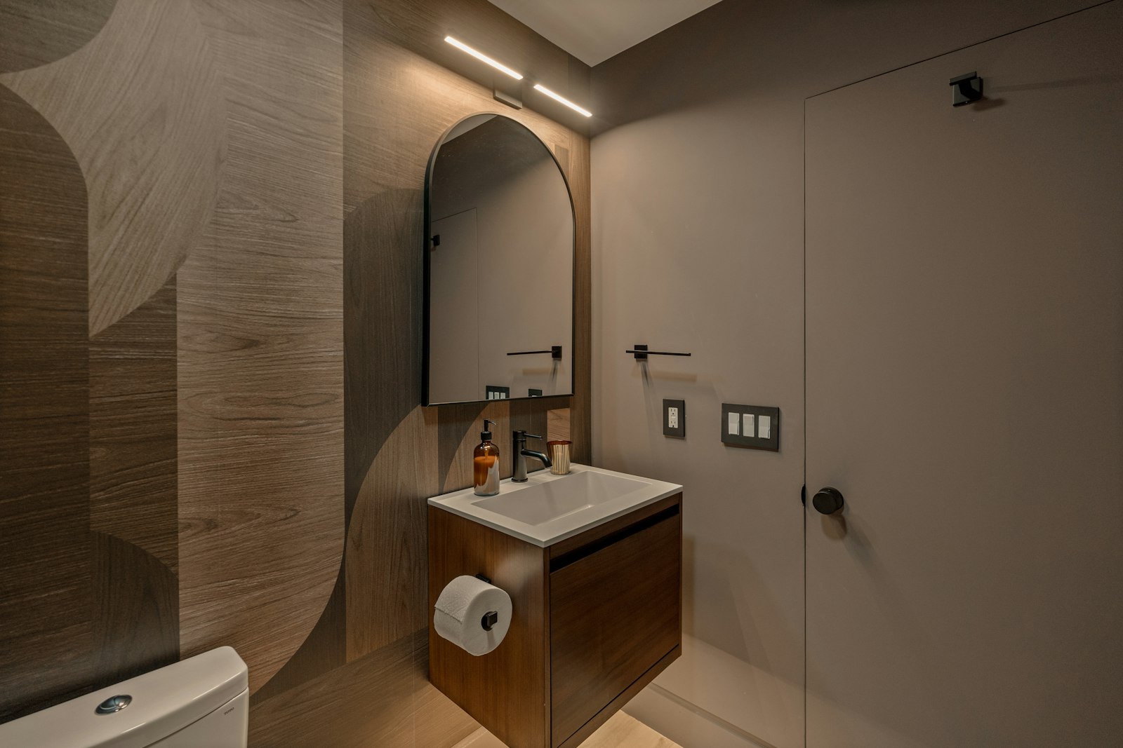 Modern bathroom with a wooden vanity and arched mirror