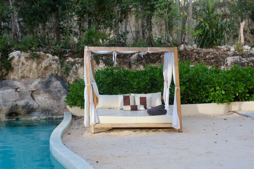 A bed sitting on top of a sandy beach next to a pool