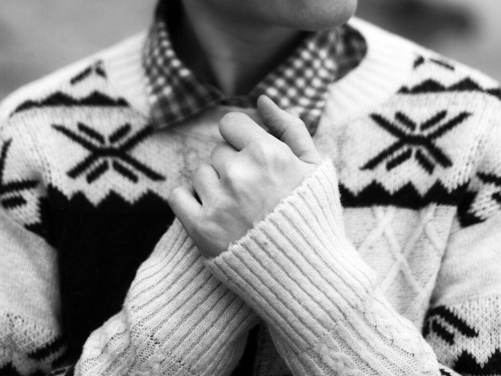 Person wearing a patterned sweater and plaid shirt
