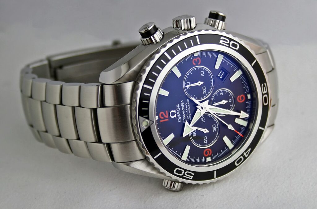 Minimalist three-hand wristwatch with a plain dial resting on a linen shirt cuff