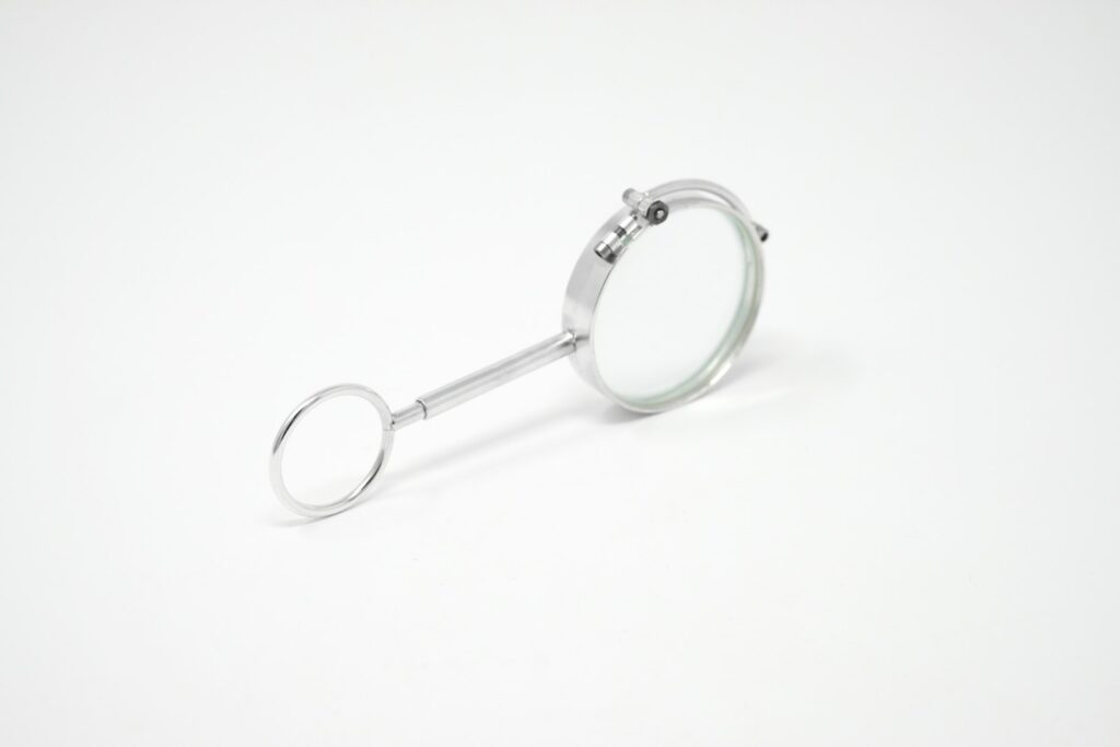 A silver magnifying glass with a circular handle on a plain white background