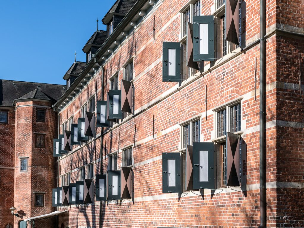 A tall brick building with many windows and shutters