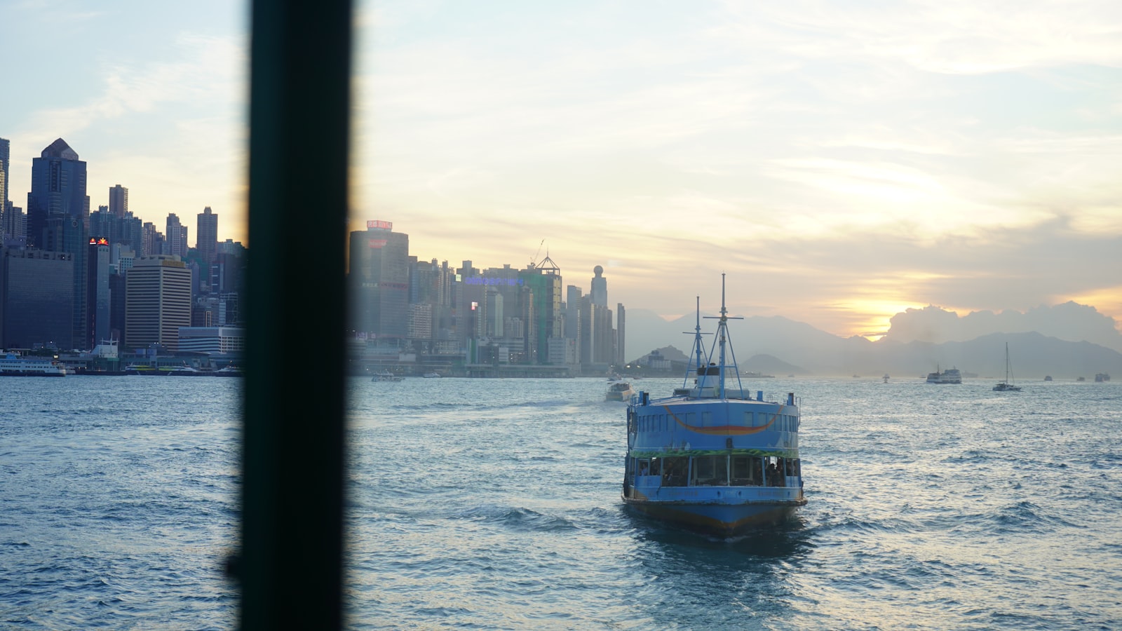 Ferry boat sails across water towards city skyline at sunset