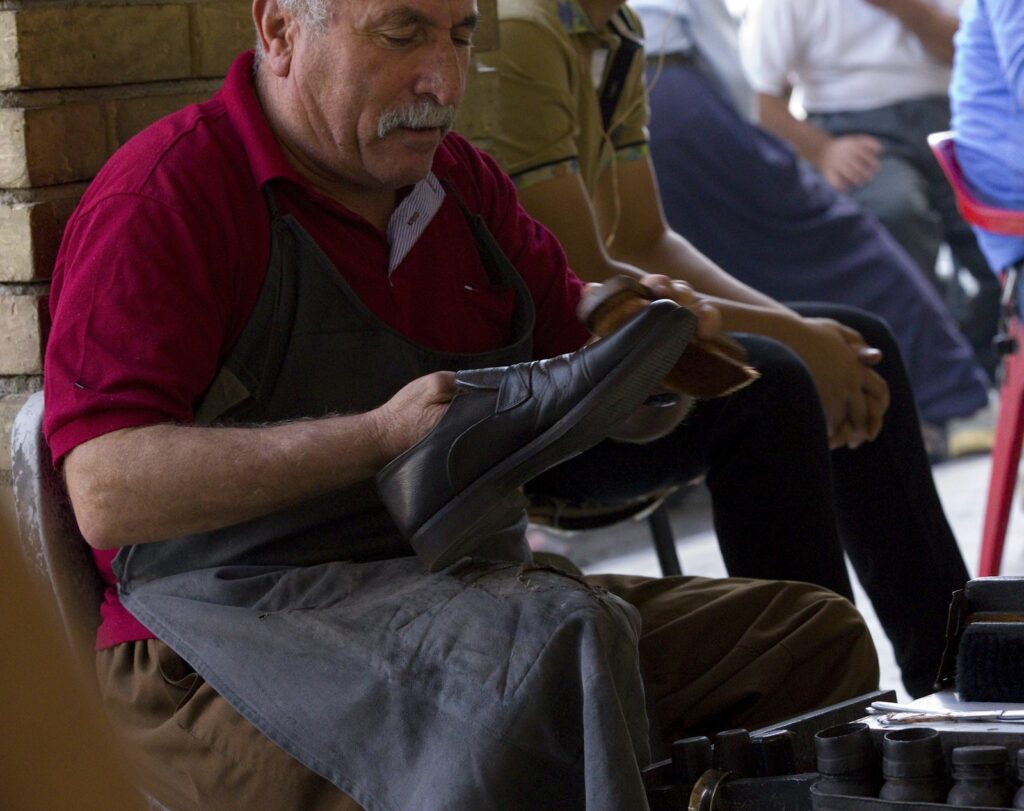 Man holding shoe wearing black apron