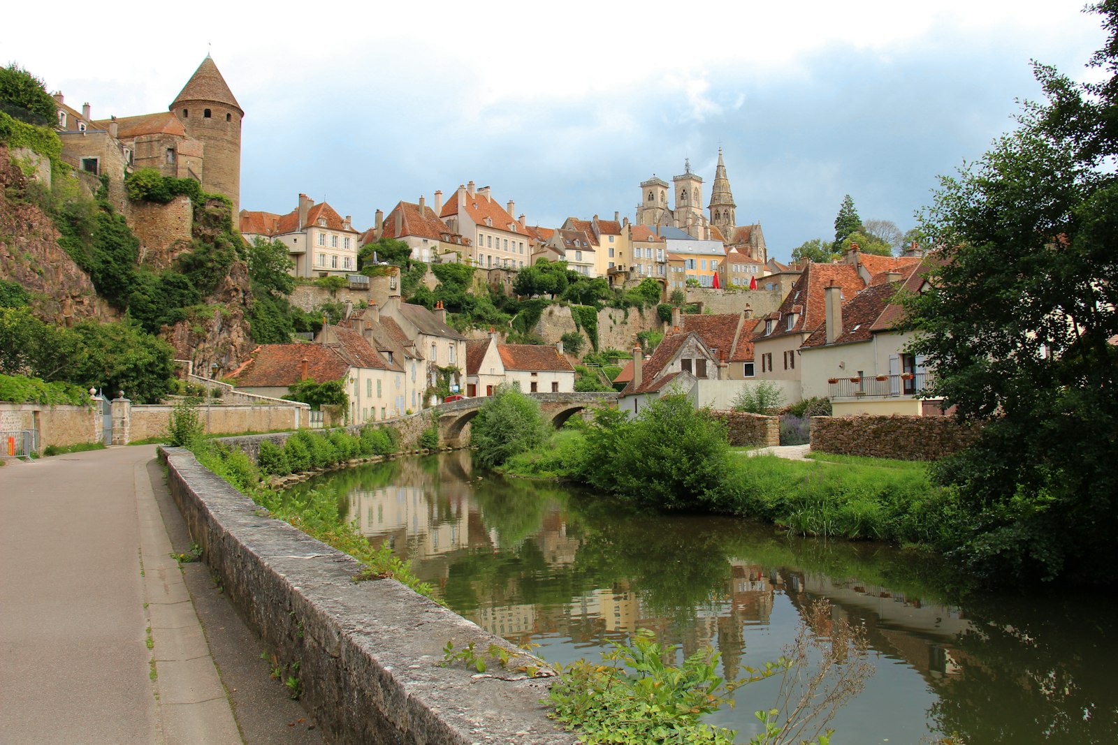 A river running through a village next to a lush green hillside