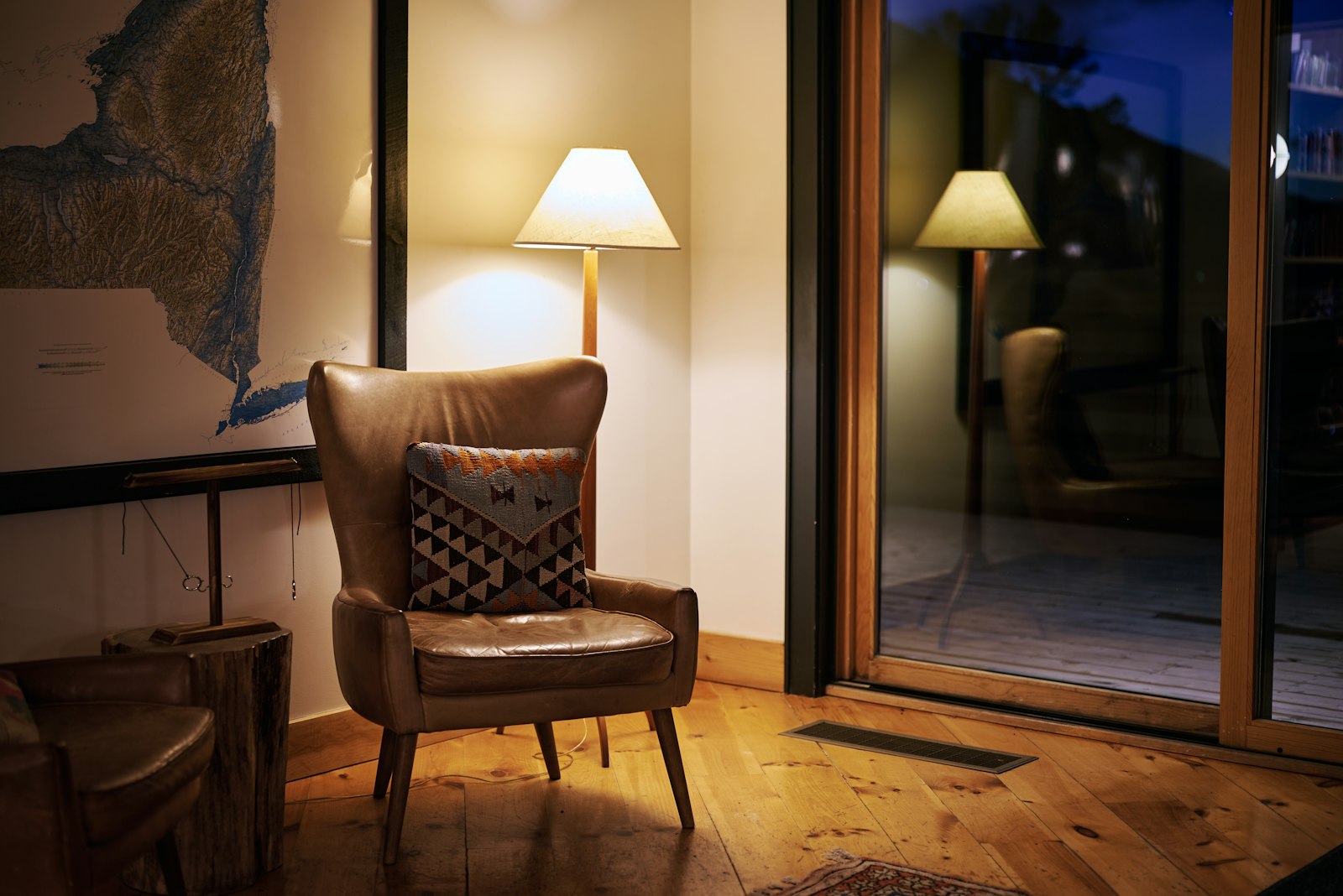 Cozy corner with a leather armchair, lamp, and map
