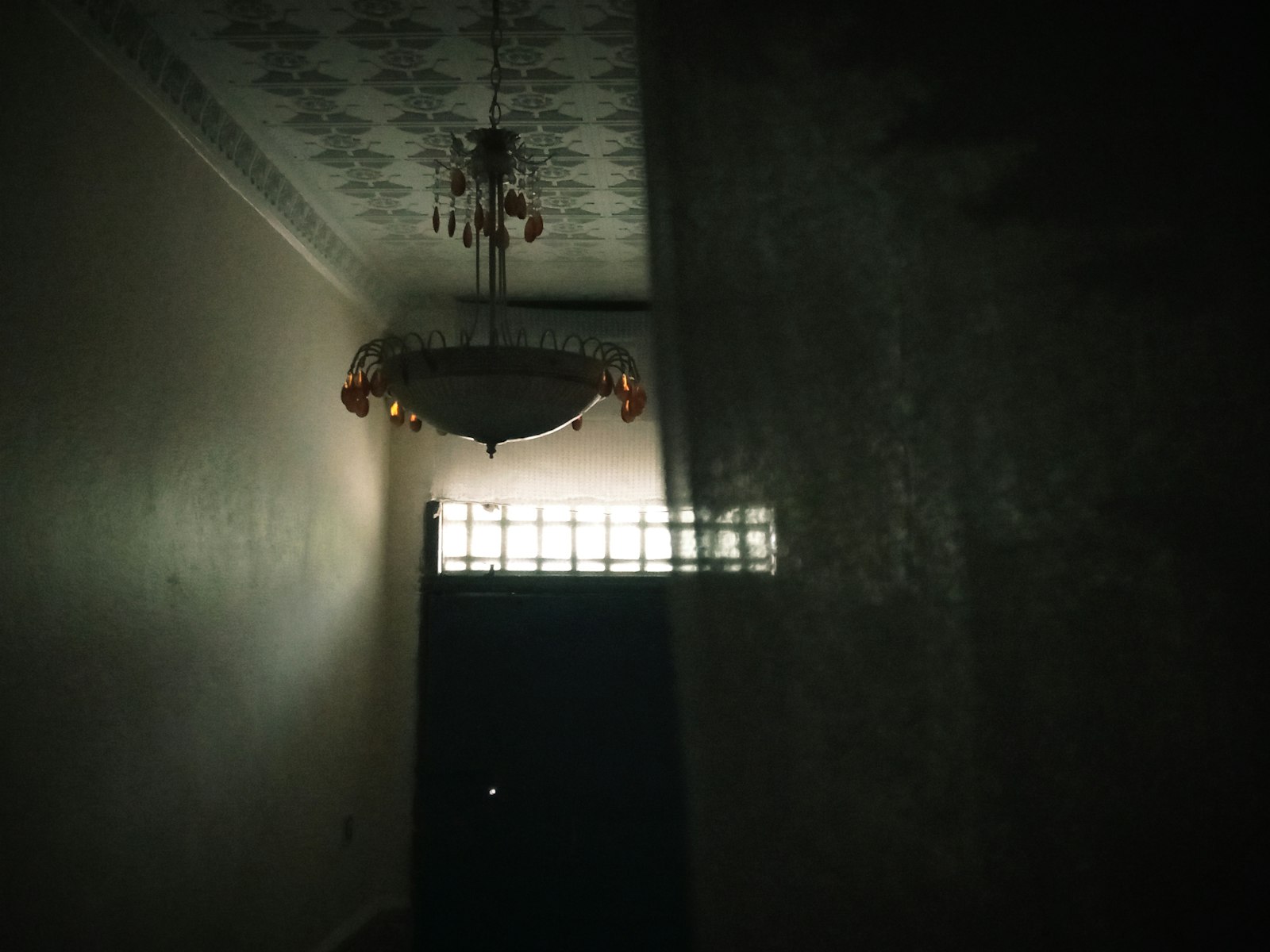 A dark hallway with a chandelier hanging from the ceiling