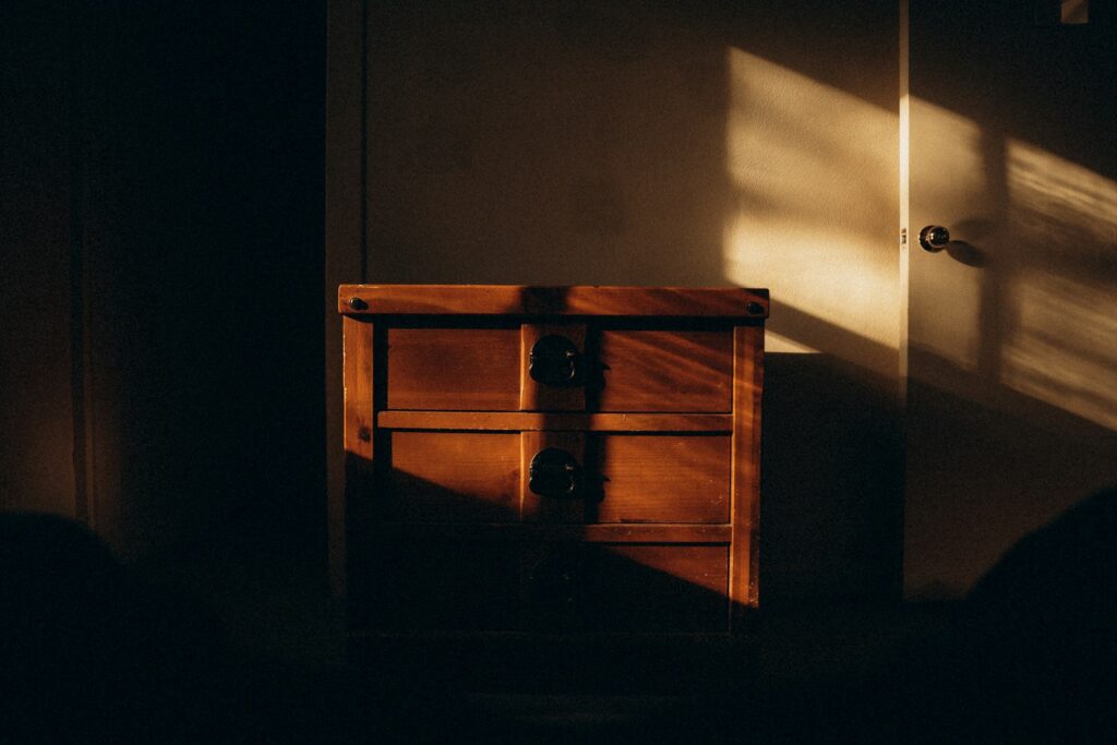 A dark room with a small chest of drawers
