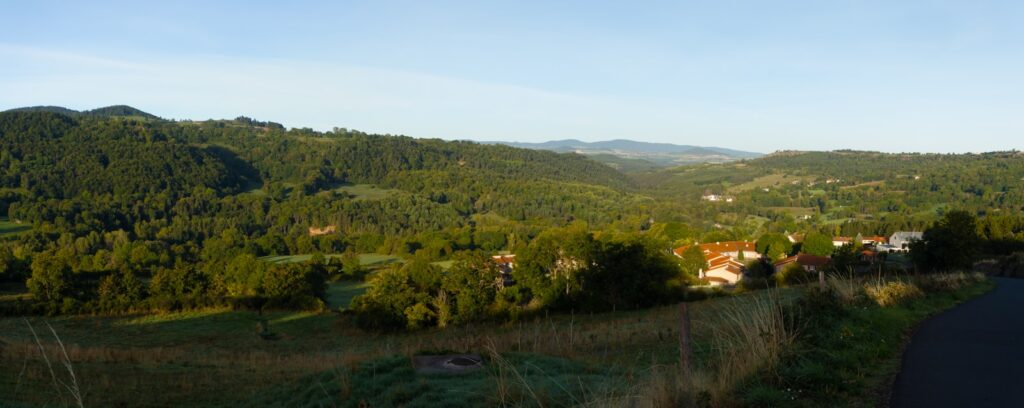 Green rolling hills with scattered houses under clear sky
