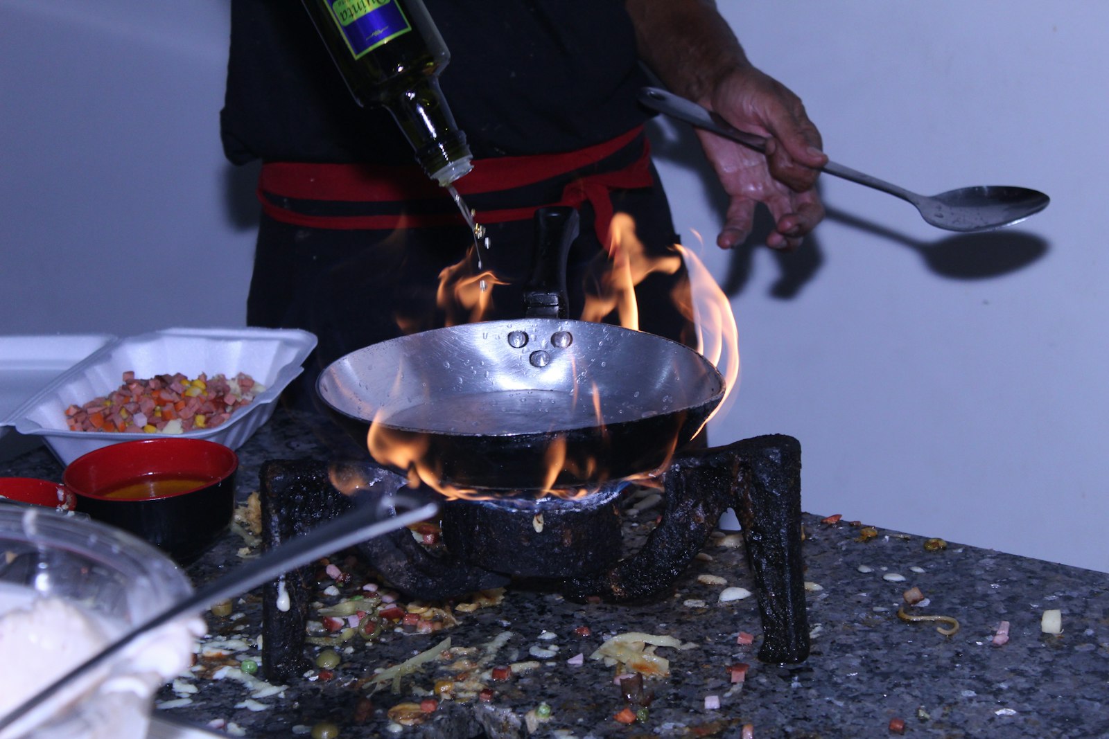 Person holding bottle and cooking pot with fire