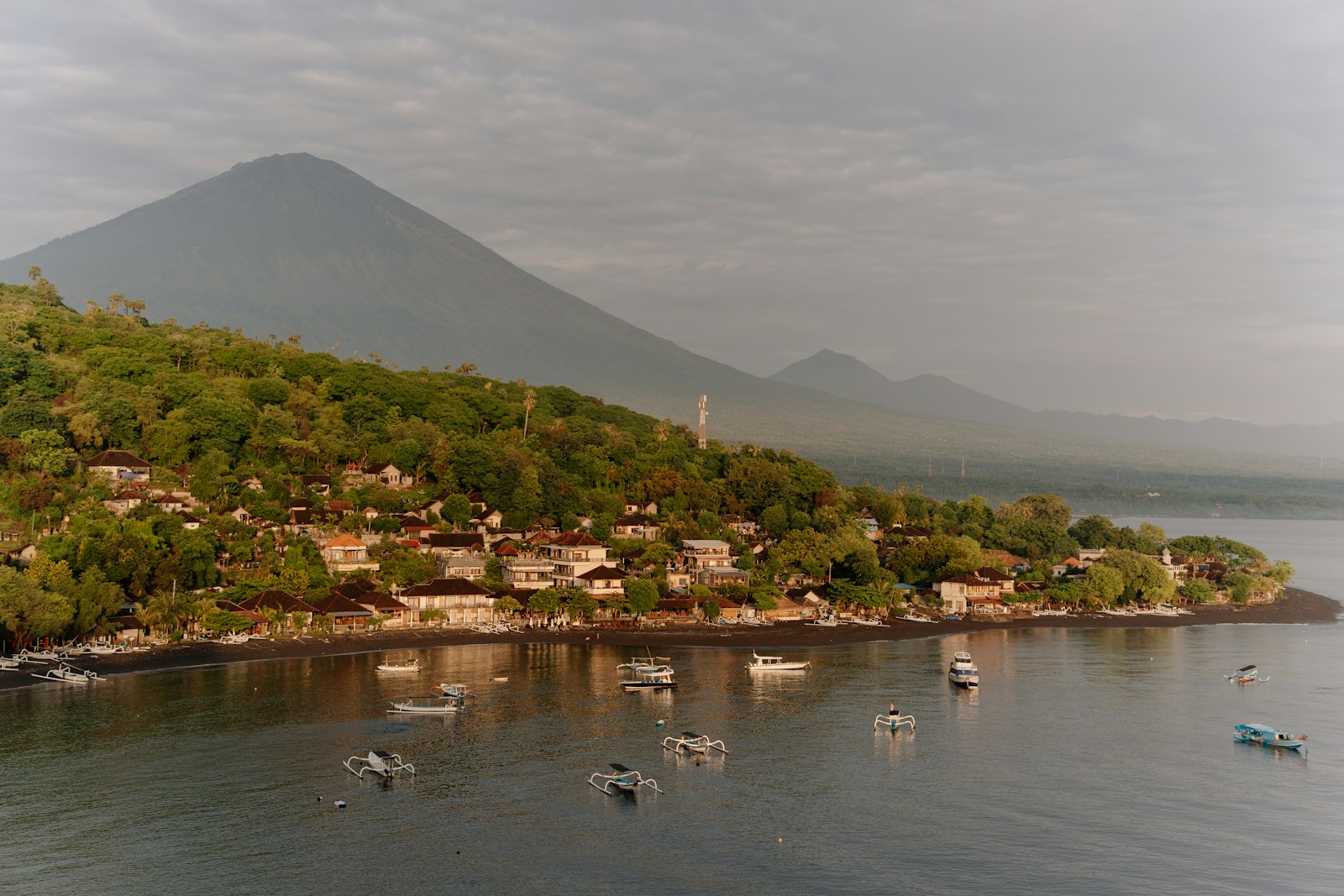 Boats in tropical bay with distant volcano