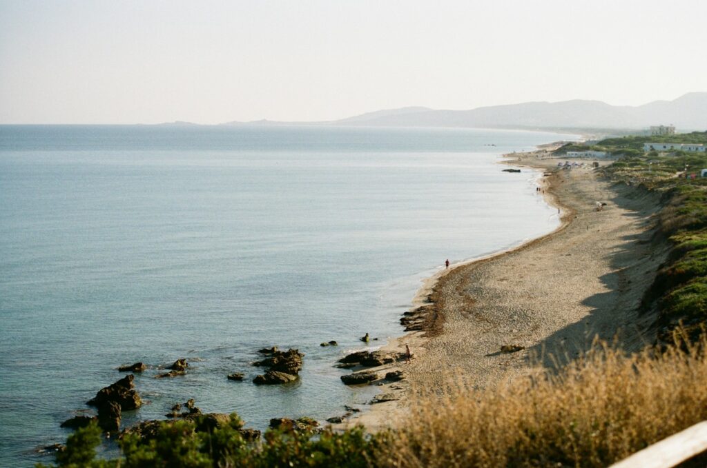 A view of a beach from a hill overlooking the ocean