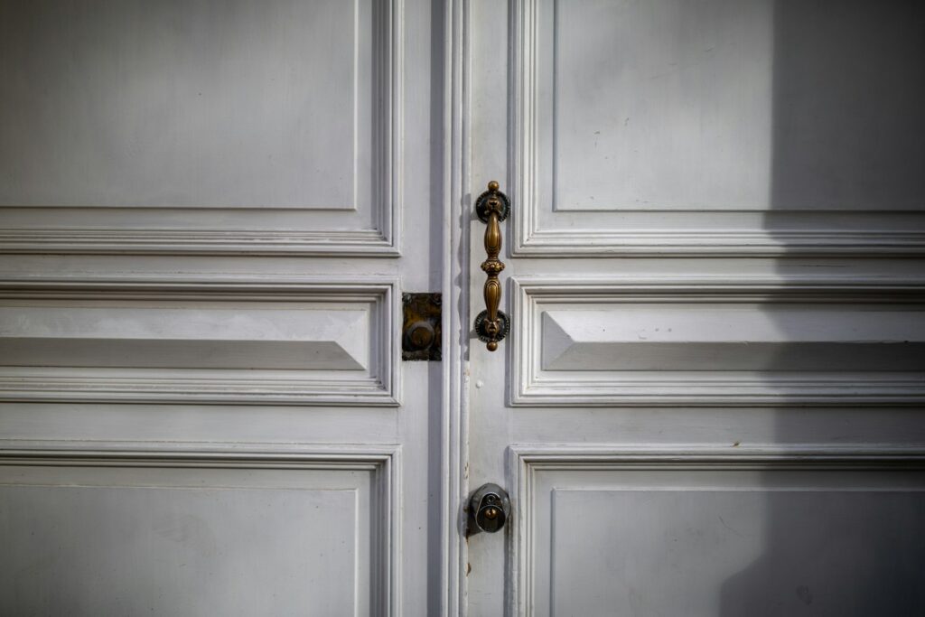 Close-up of a white wooden door with ornate handles