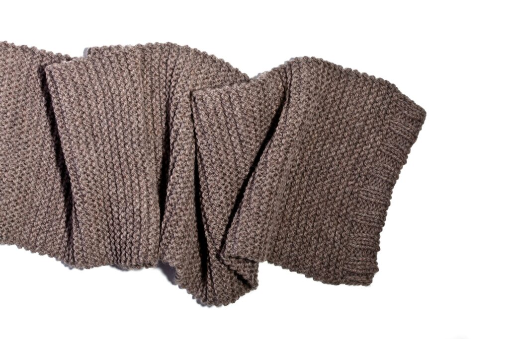 A pair of brown knitted gloves on a white background