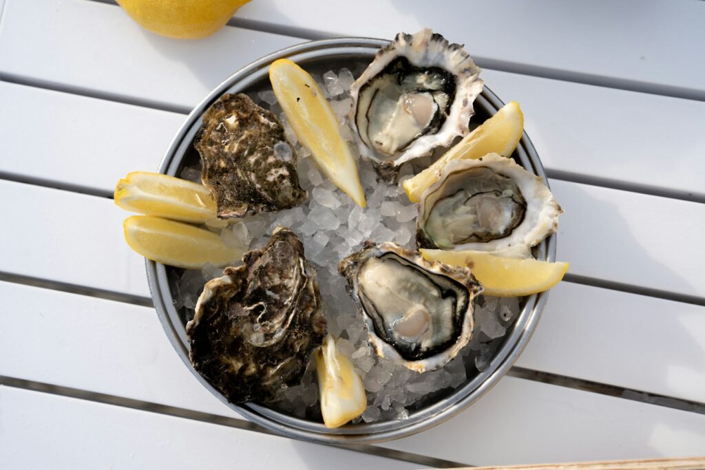A plate of oysters on a table with lemon wedges