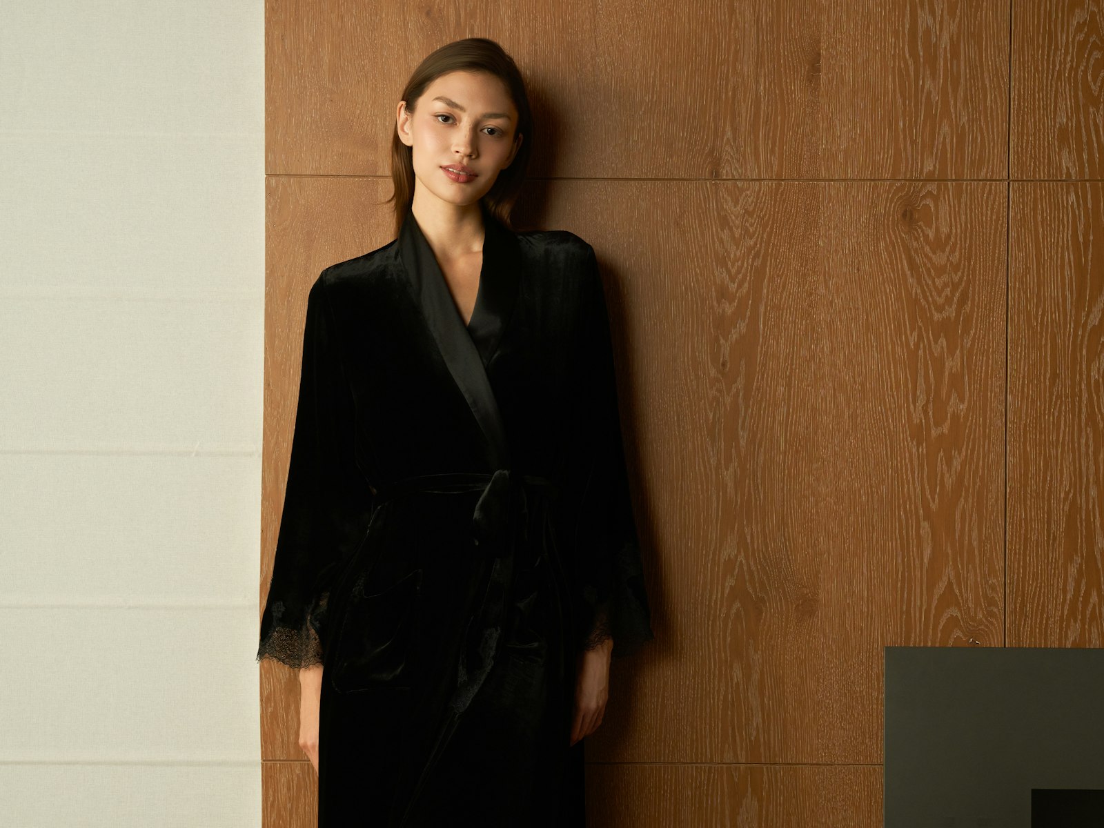 Woman in a black velvet robe standing indoors