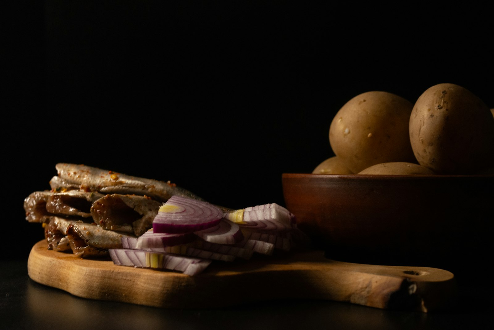 A wooden cutting board topped with meat and potatoes